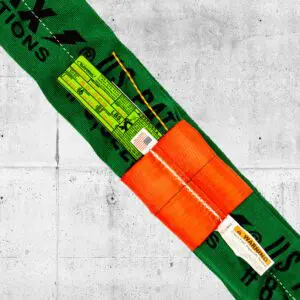 Close-up of green Twin-Path synthetic roundsling with orange Check-Fast cover and indicator string sticking out, designed for heavy lifting applications.